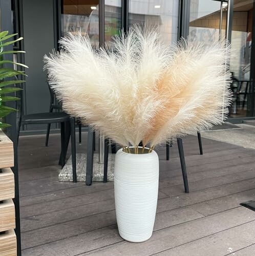 White vase with pampas grass on a wooden deck