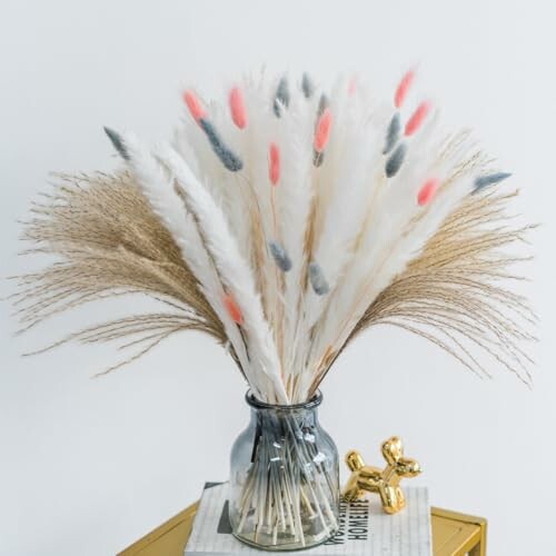 Vase with pampas grass and decorative items on table. The 80 Pcs Dried Pampas Grass Decor is perfect for creating stunning centerpieces!